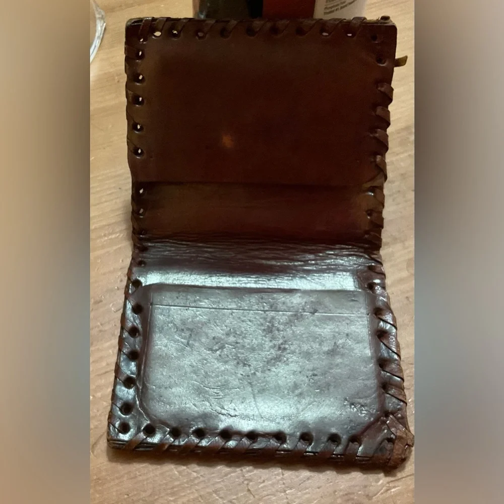 Hand crafted tooled mens leather design bifold wallet laced stitching around it.